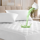 Quilted waterproof mattress protector on a bed in a bright bedroom