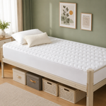 Quilted waterproof mattress protector on a bed in a bright bedroom